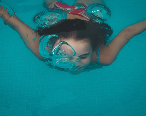 Mädchen schwimmt unter Wasser im Schwimmbad